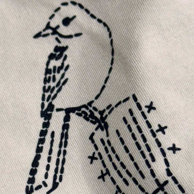 Embroidered design of a bird on a white fabric background