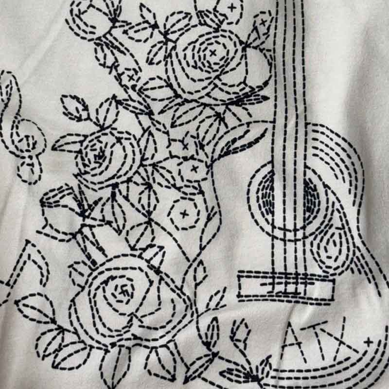 Embroidered fabric with floral and musical instrument patterns on a white background