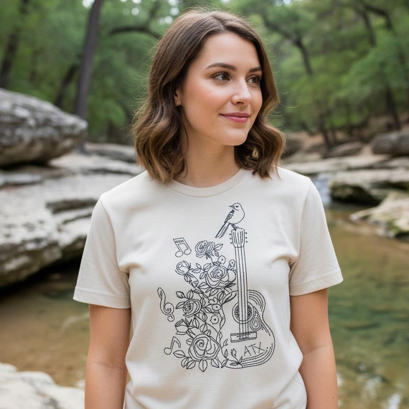 Woman wearing a white t-shirt with a black graphic design in a natural setting