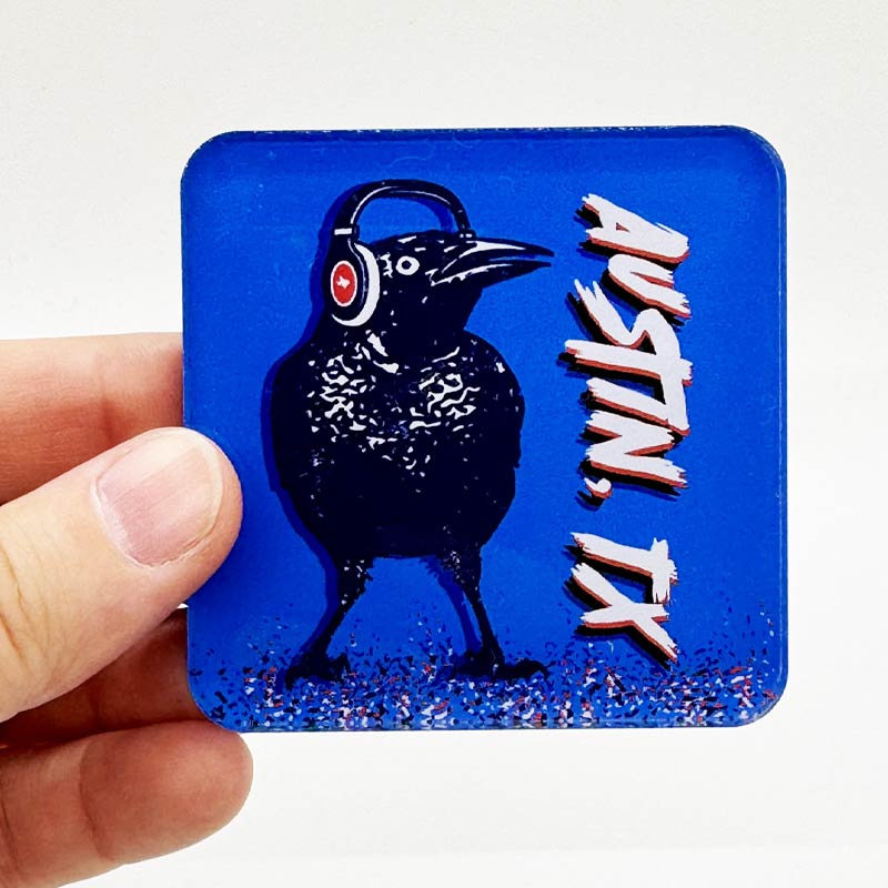 Acrylic magnet featuring a cartoon grackle wearing headphones, inspired by Austin, Texas culture.