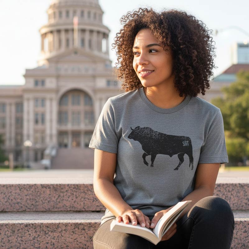 Woman sitting outdoors reading a book with a building in the background