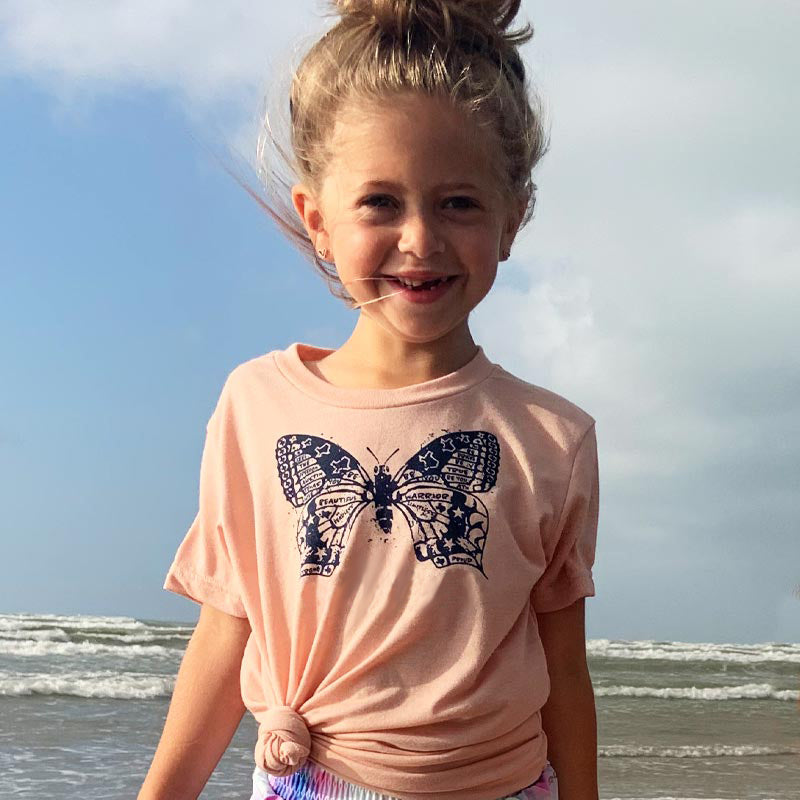 Model wearing our Butterfly ATX youth t-shirt with vibrant butterfly graphic – fun and whimsical Austin-themed tee for kids