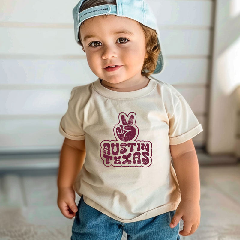Little model wearing our Funky Town ATX toddler t-shirt with retro-style graphic – fun and colorful Austin tee for kids