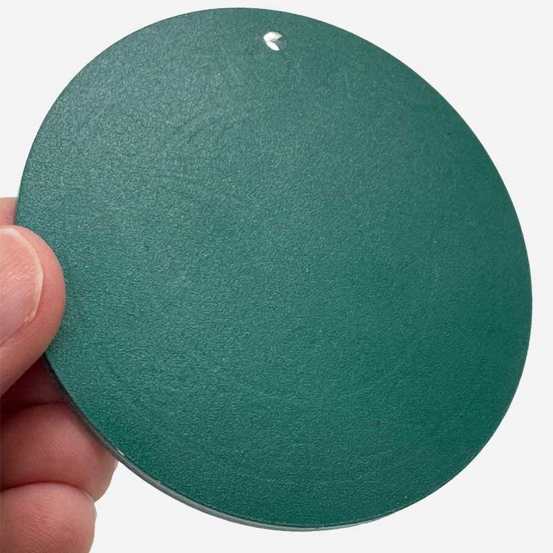 Round green sandpaper disc held by a hand against a white background