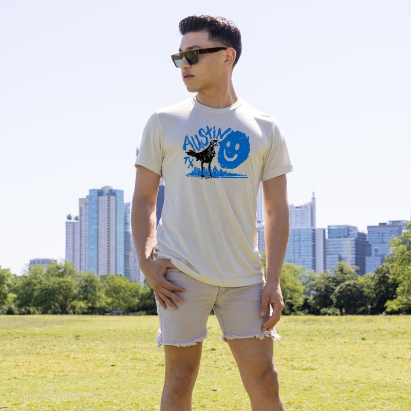 Person wearing Happy Grackle ATX t-shirt featuring playful grackle graphic – soft and casual streetwearear