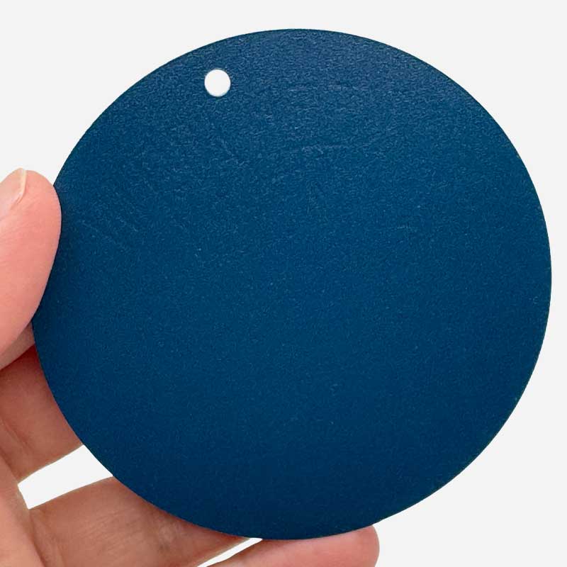 Hand holding a blue circular object with a white hole on a white background