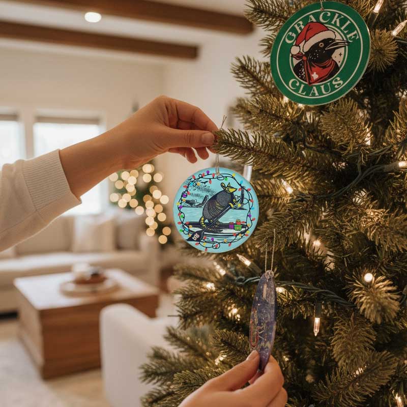 Person decorating a Christmas tree with ornaments, including a Crackle Claus ornament.