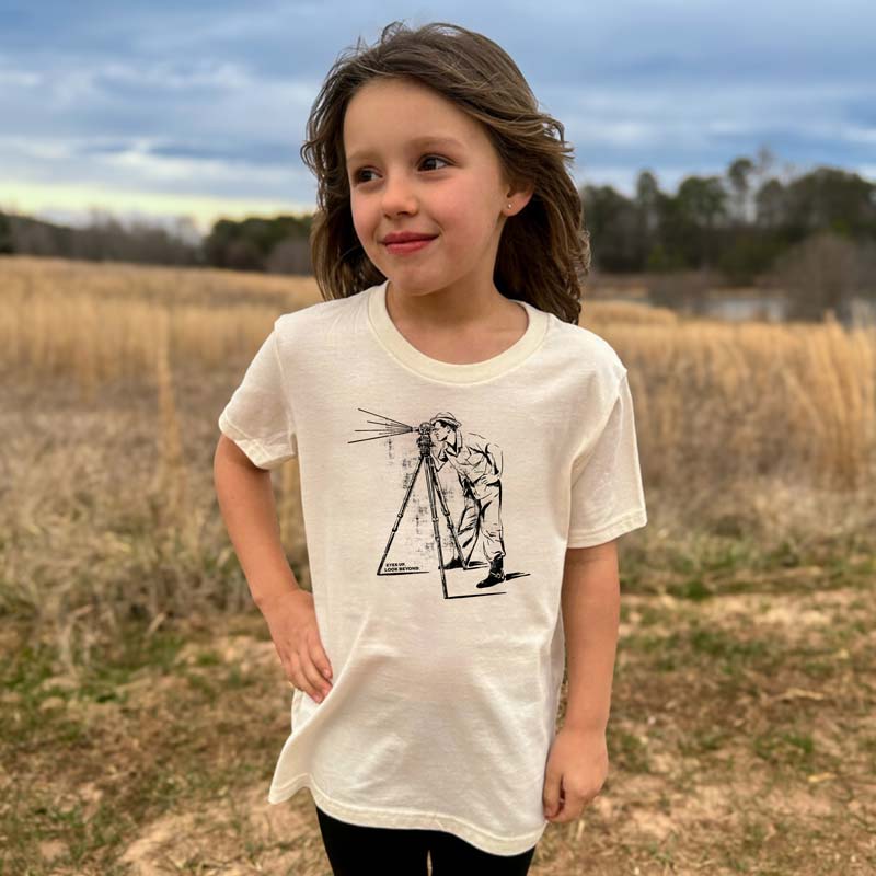 Youth t-shirt featuring vintage photo of man looking through a telescope with "Look Beyond" text – inspirational space-themed graphic on soft cotton tee.