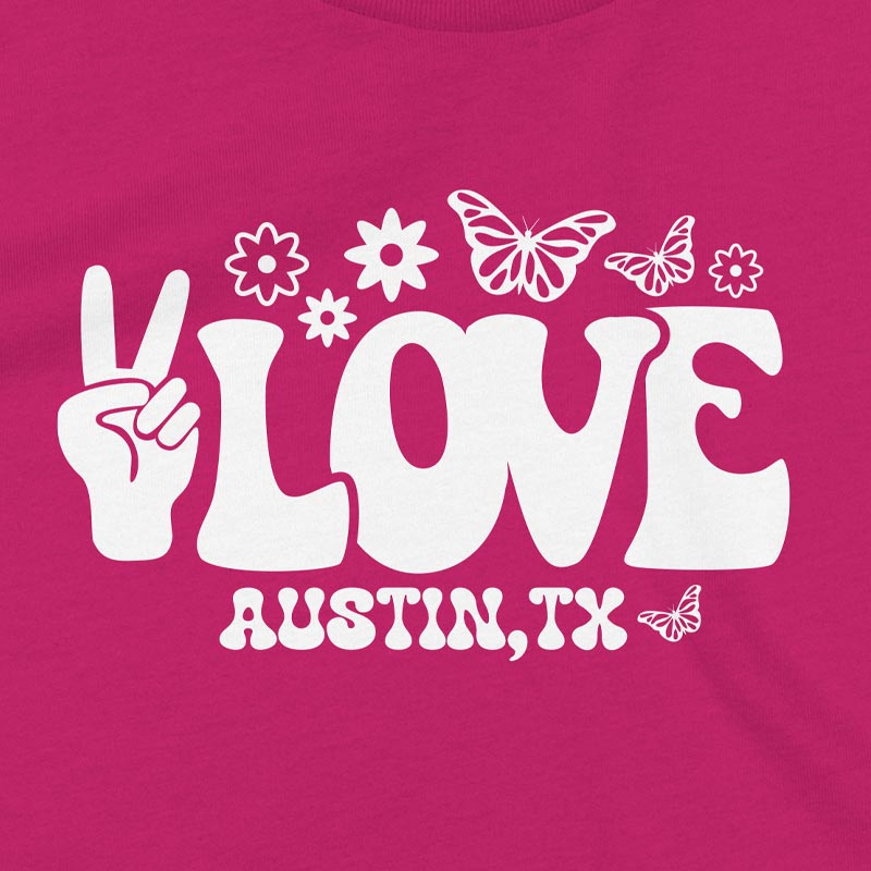 Pink t-shirt with white 'LOVE AUSTIN, TX' design featuring a peace sign, flowers, and butterflies.