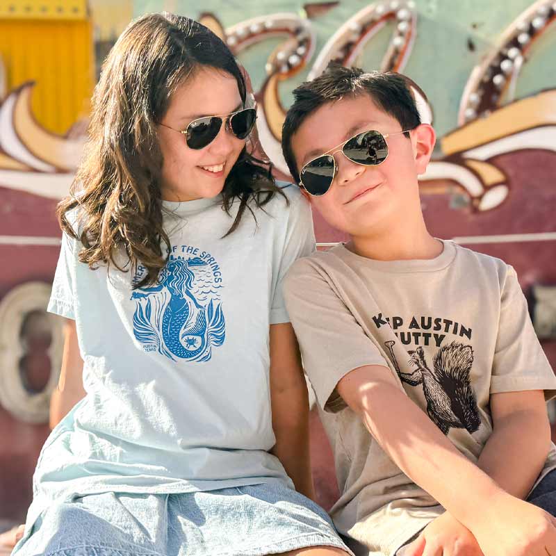 Two children wearing sunglasses in front of a colorful background