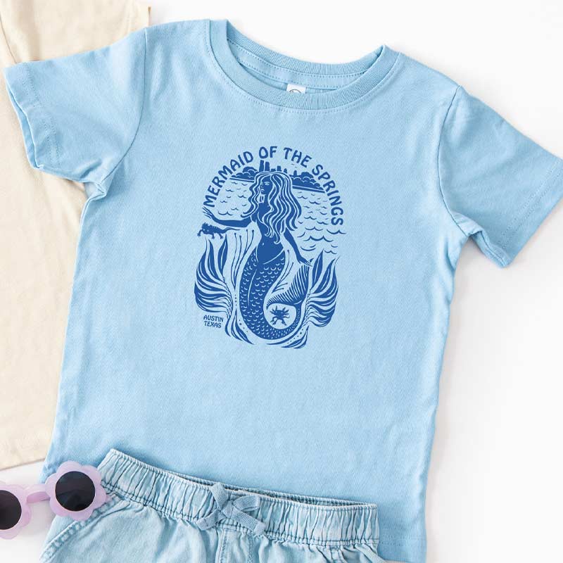 Light blue t-shirt with mermaid graphic and text on a white background