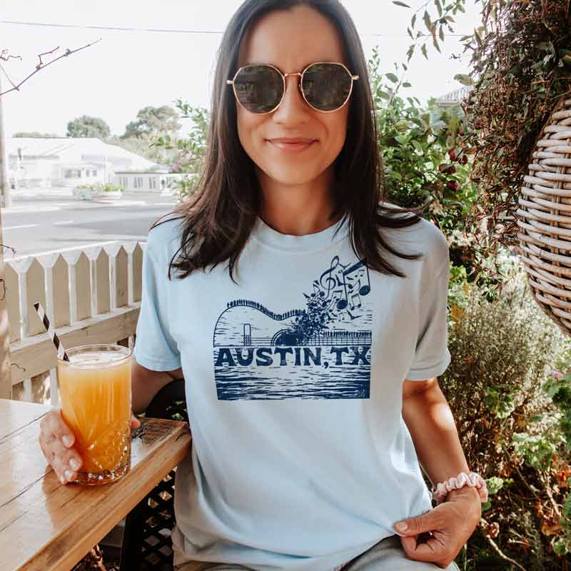 Model wearing ATX Music Bridge T-shirt, blending city skyline and live music theme