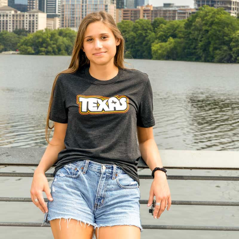 Model wearing Retro Texas T-shirt with bold vintage typography, standing outdoors in natural light