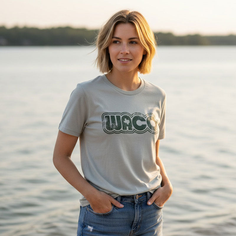 Woman wearing a t-shirt with 'WACO' logo by a body of water