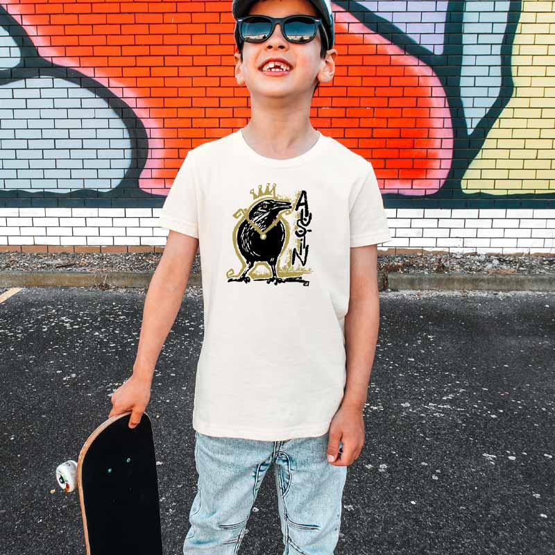 Youth wearing Royal Squawk Austin t-shirt featuring a crown-wearing grackle – fun and stylish ATX tee for kids