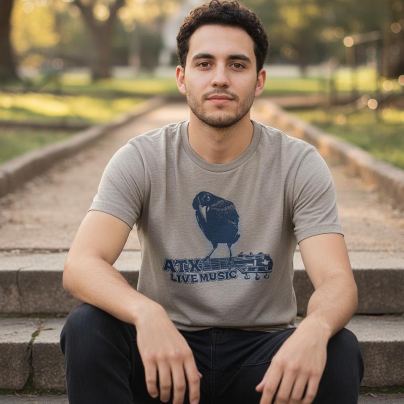 Man wearing a gray t-shirt with a graphic design sitting on steps outdoors.
