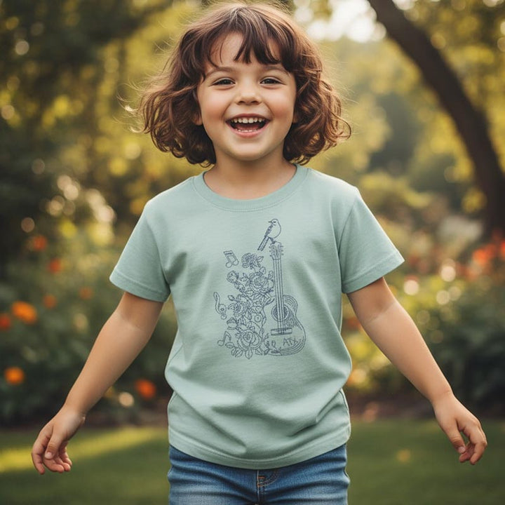 Child wearing a light green t-shirt with a graphic design outdoors