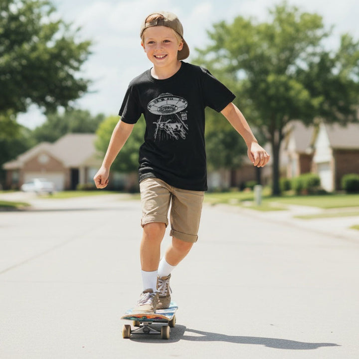 Child skateboarding on a suburban street with houses and trees in the background