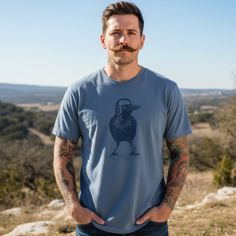 Man wearing a blue t-shirt with a bird graphic outdoors