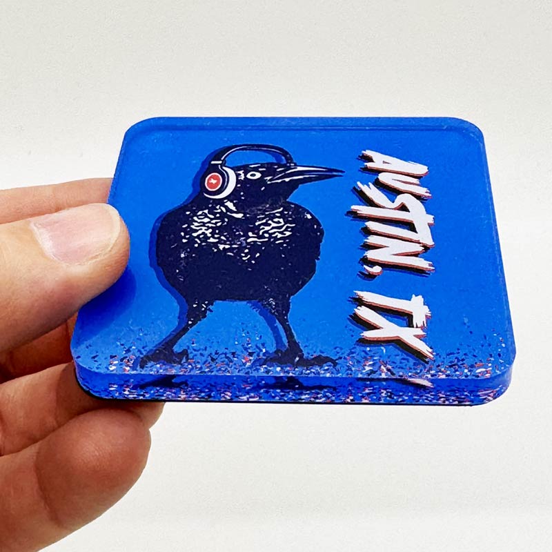 Acrylic magnet featuring a cartoon grackle wearing headphones, inspired by Austin, Texas culture.