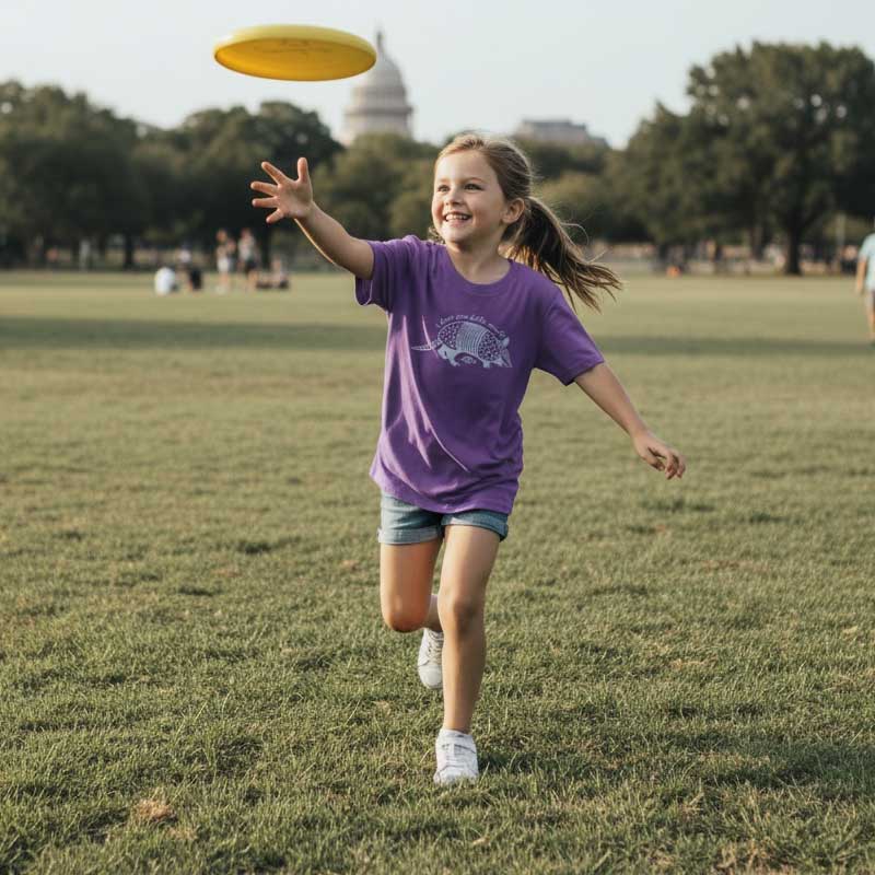 Girl in a purple shirt running with a yellow frisbee in a park