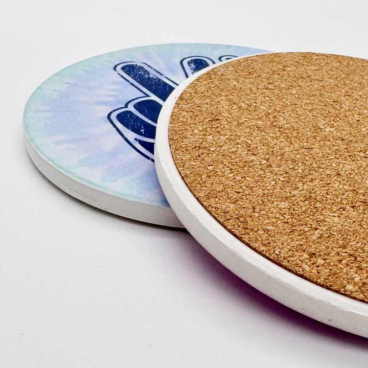 Two coasters with one having a cork back and the other with a blue and white design.