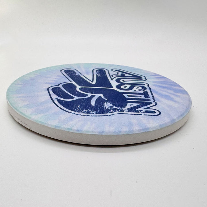 Round coaster with blue hand sign and 'Peace' text on a tie-dye background