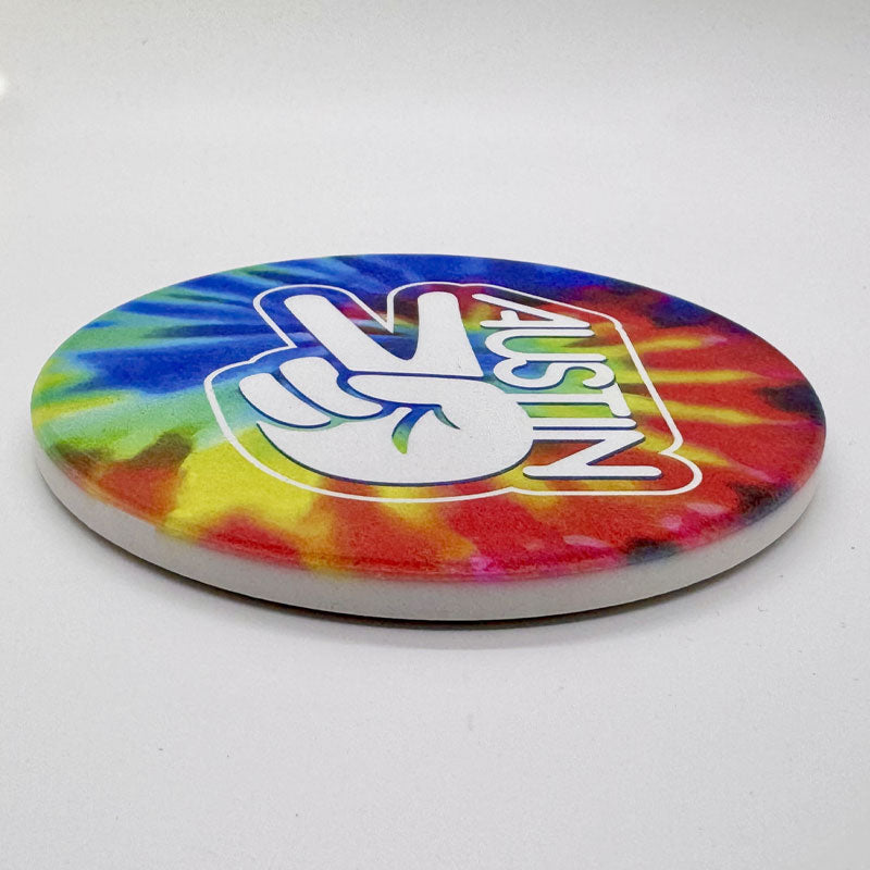 Colorful tie-dye coaster with a Peace Austin design on a white background