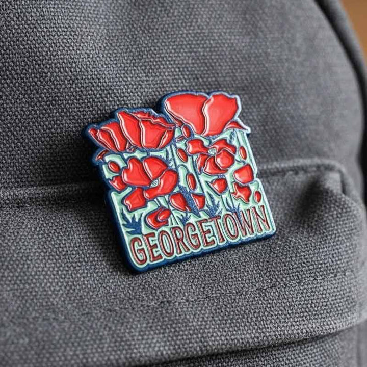 Georgetown-themed pin with red flowers on a gray fabric background