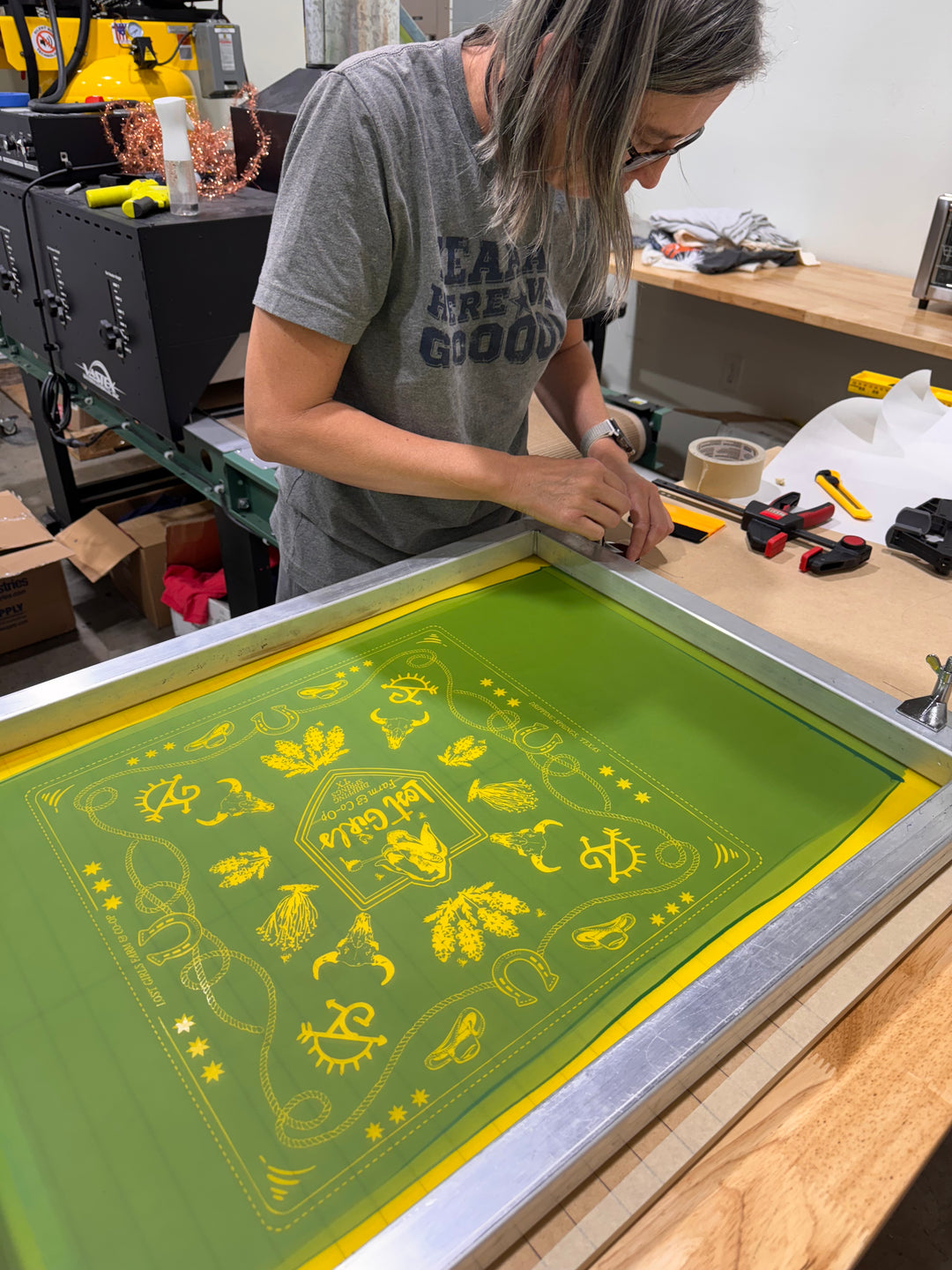 Person working on a green screen with yellow designs in a workshop setting