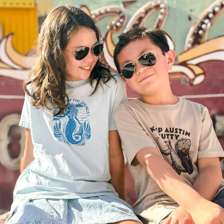 Two children wearing sunglasses in front of a colorful background