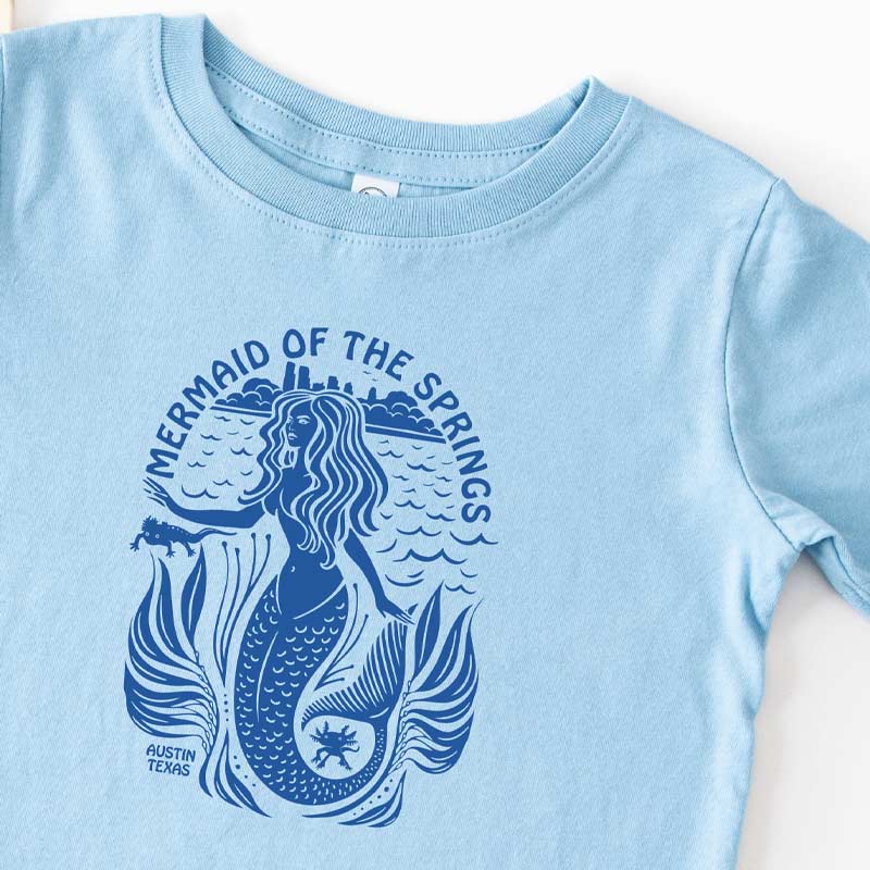 Light blue t-shirt with a mermaid graphic and text on a white background