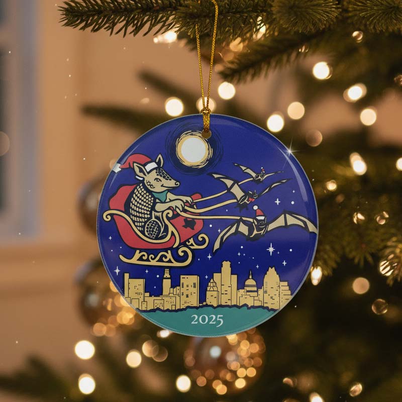 Merry Christmas Armadillo Ornament with a cityscape and Santa-like figure, hanging on a tree.