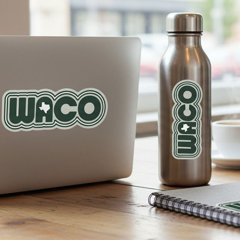 Laptop with Waco sticker and water bottle with Waco logo on a wooden surface.