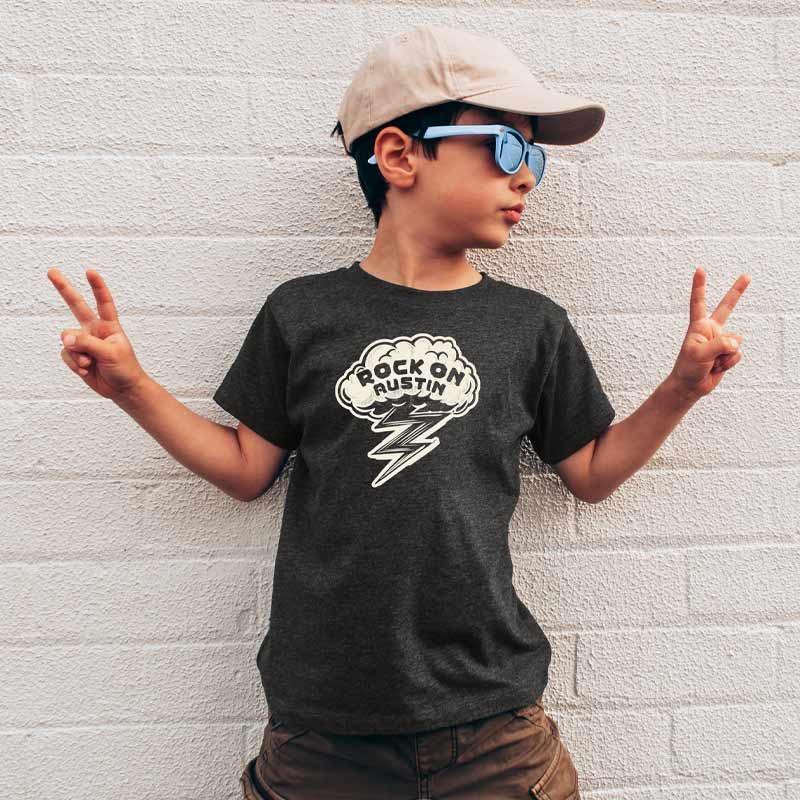 Model wearing our Rock On Austin youth t-shirt with bold lightning bolt graphic – fun and energetic music tee for kids