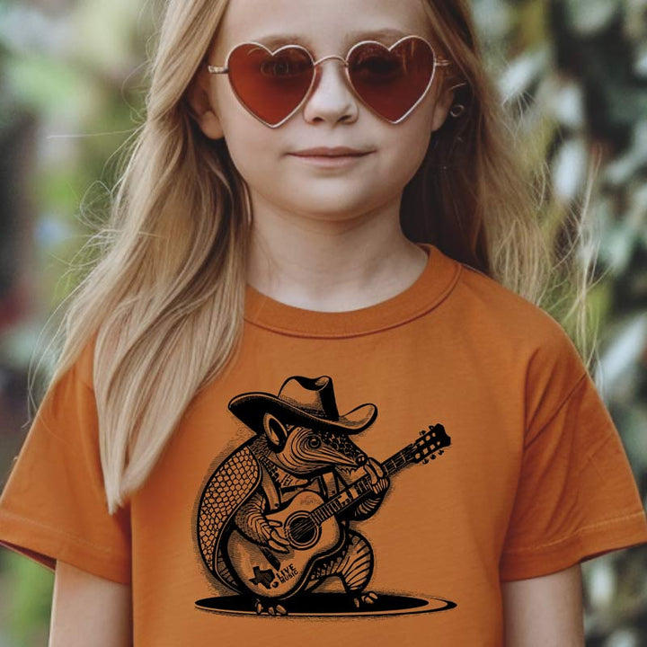 Model wearing our Rockin’ Armadillo youth t-shirt with cartoon armadillo playing guitar – fun Texas music tee for kids