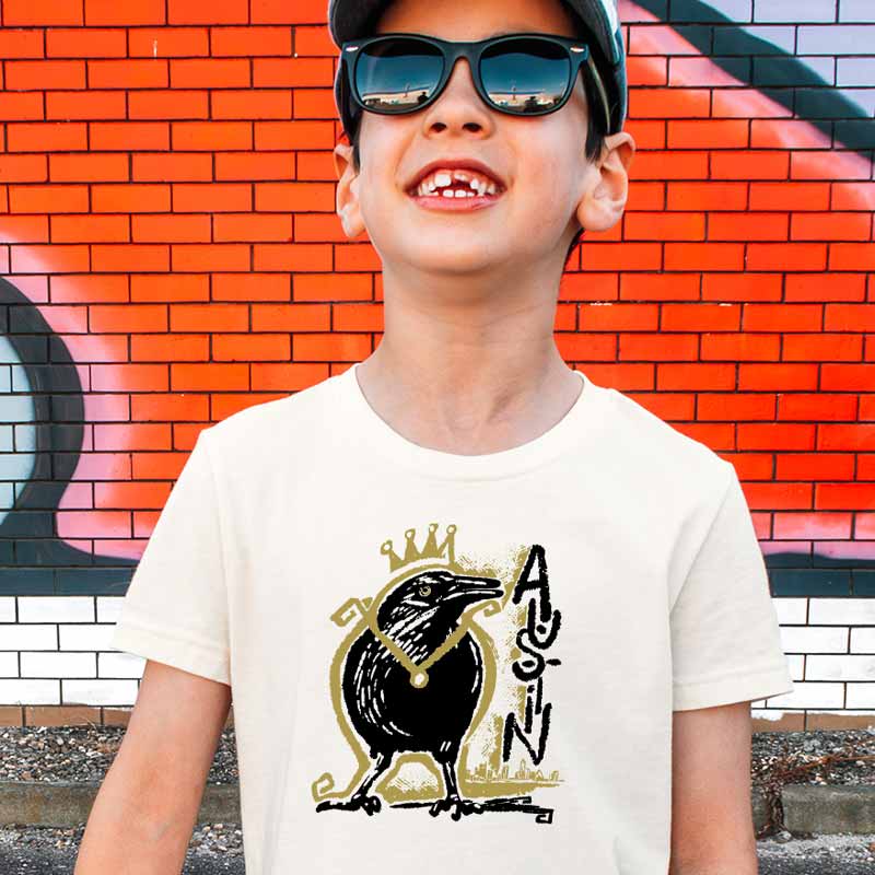 Youth wearing Royal Squawk Austin t-shirt featuring a crown-wearing grackle – fun and stylish ATX tee for kids