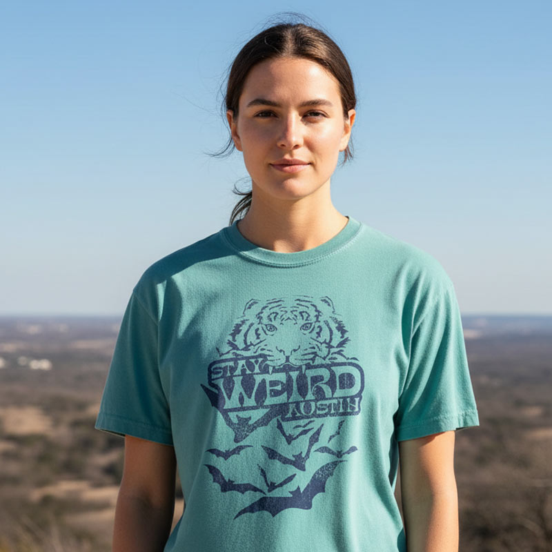 Person wearing a teal t-shirt with a graphic design outdoors