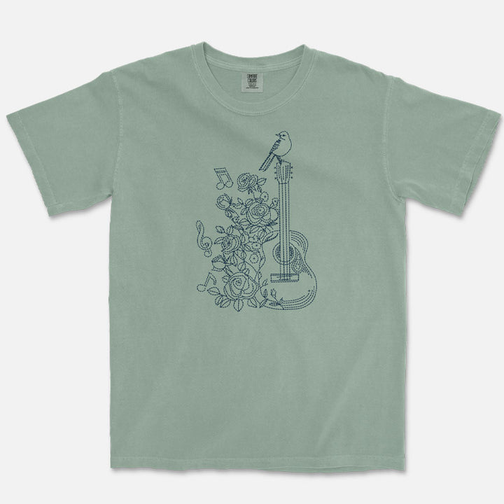 Green t-shirt with floral and guitar design on a white background