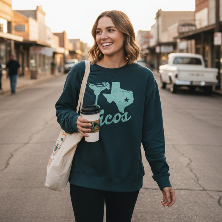 Woman in a dark green sweatshirt with a Texas design walking down a street.