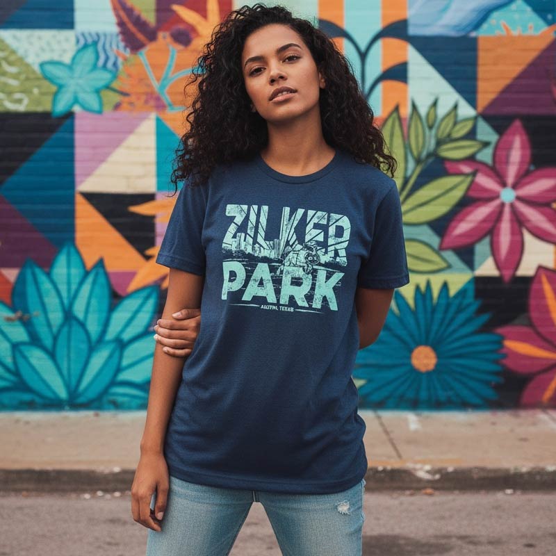 Woman wearing a blue t-shirt with 'Zilker Park' text in front of a colorful mural.