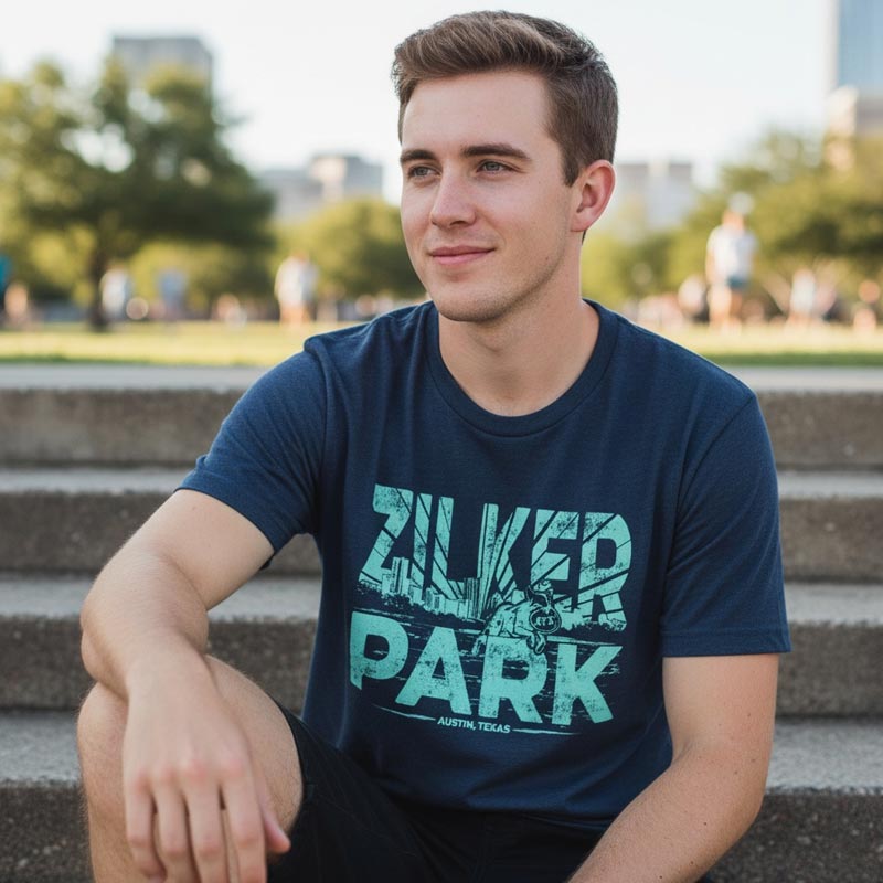 Man wearing a blue t-shirt with 'Silver Park' text sitting on steps outdoors.