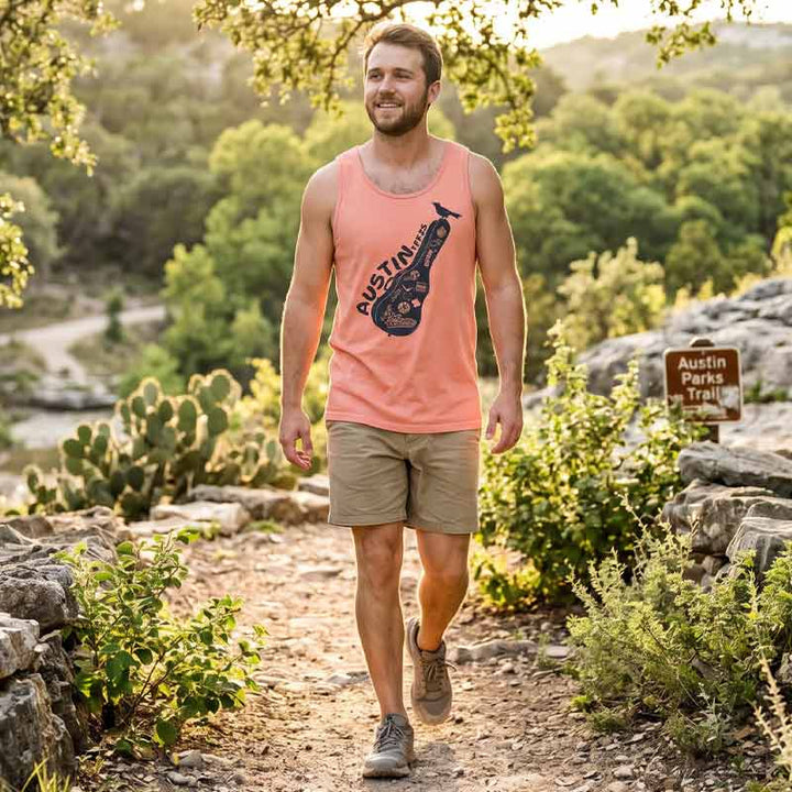 Man wearing the Carry-On Austin tank top in Terracotta while walking a scenic Austin, Texas trail surrounded by limestone, trees, and Hill Country scenery.
