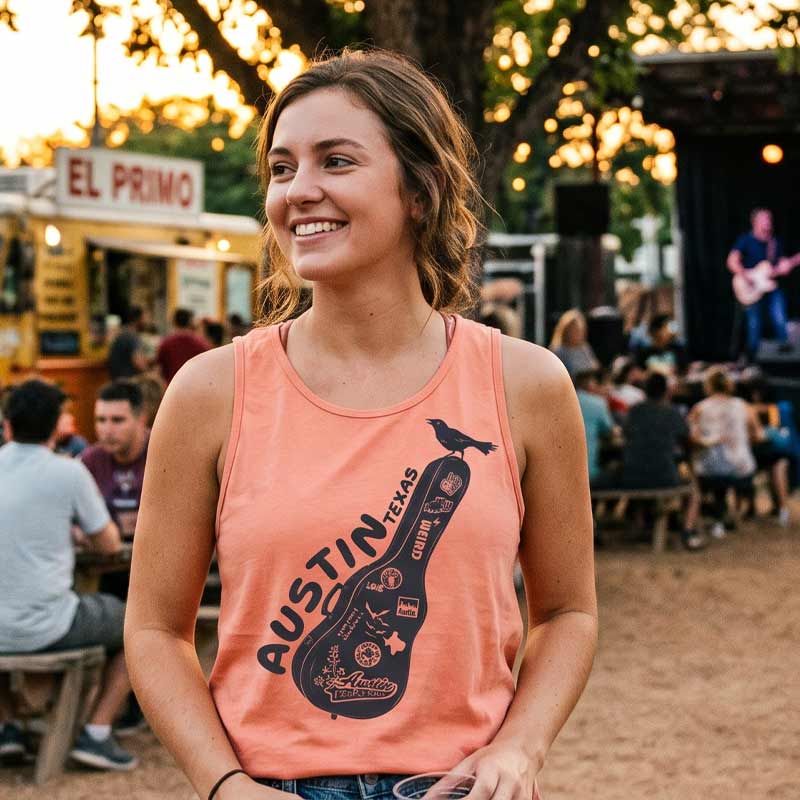 Woman wearing an 'Austin, Texas' tank top at a lively outdoor event with food trucks and people in the background.