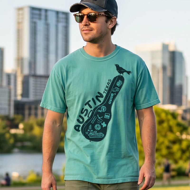 Man wearing a teal t-shirt with 'Austin Texas' design against a cityscape background