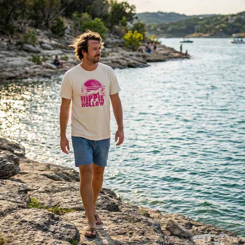 Man walking along a rocky shoreline with a scenic water background