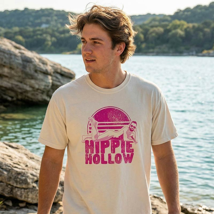 Man wearing a t-shirt with 'Hippie Hollow' design by a lake
