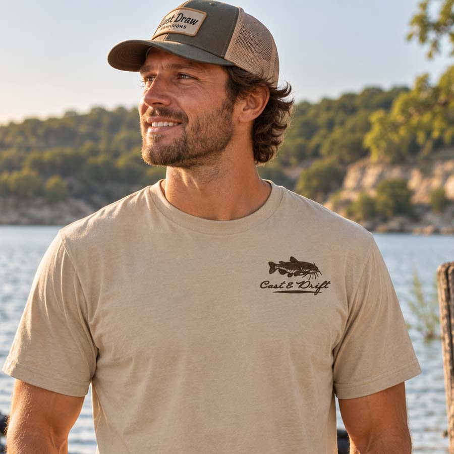 A man wearing a beige short-sleeve t-shirt with a black fish logo and the text &