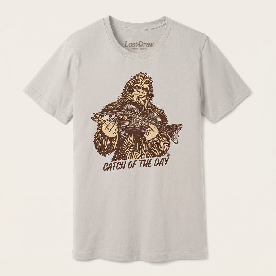 Catch of the Day Walleye Tee in BELLA+CANVAS Dust, featuring a vintage Bigfoot holding a walleye fish on the front.
