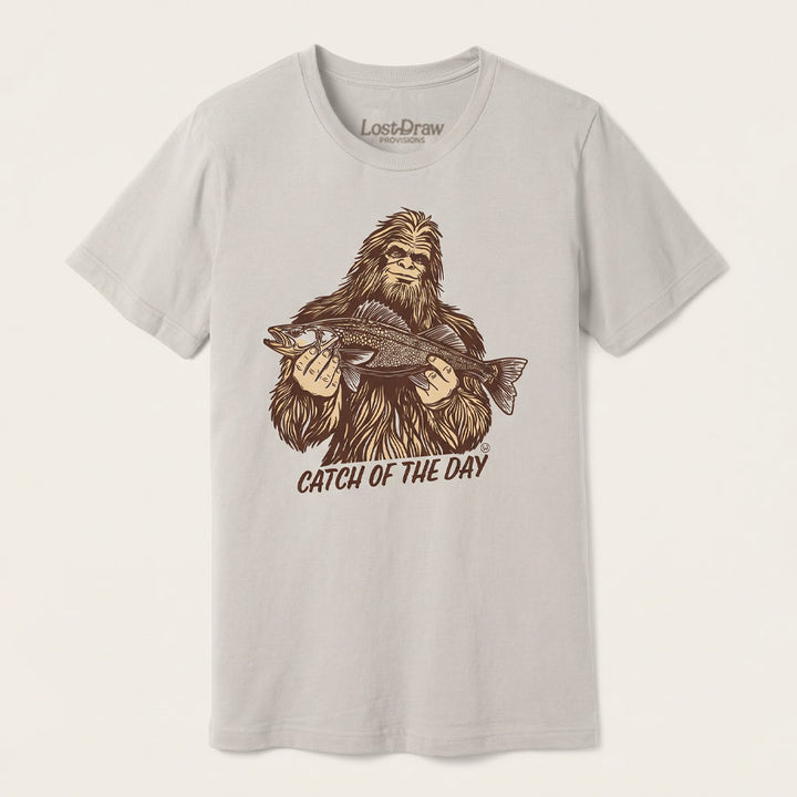 Catch of the Day Walleye Tee in BELLA+CANVAS Dust, featuring a vintage Bigfoot holding a walleye fish on the front.
